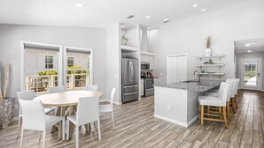 A modern kitchen with white cabinetry, stainless steel appliances, and a dining area with a round table and white chairs. - Dog-Friendly House with Private Pool (Santa Rosa Beach)