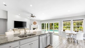 A modern kitchen with a granite countertop, white cabinetry, and a built-in dishwasher. - Dog-Friendly House with Private Pool (Santa Rosa Beach)
