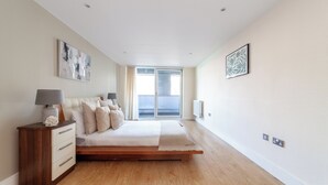 A bedroom with a bed, bedside table, and artwork on the walls. - Cosy 1 Bed Flat in Greenwich (London)
