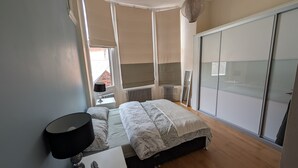 A bedroom with a bed, bedside table, lamp, and a wardrobe.