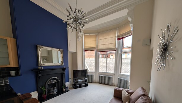 A living room with a fireplace, a sofa, a TV, and a large window with a view of the city.