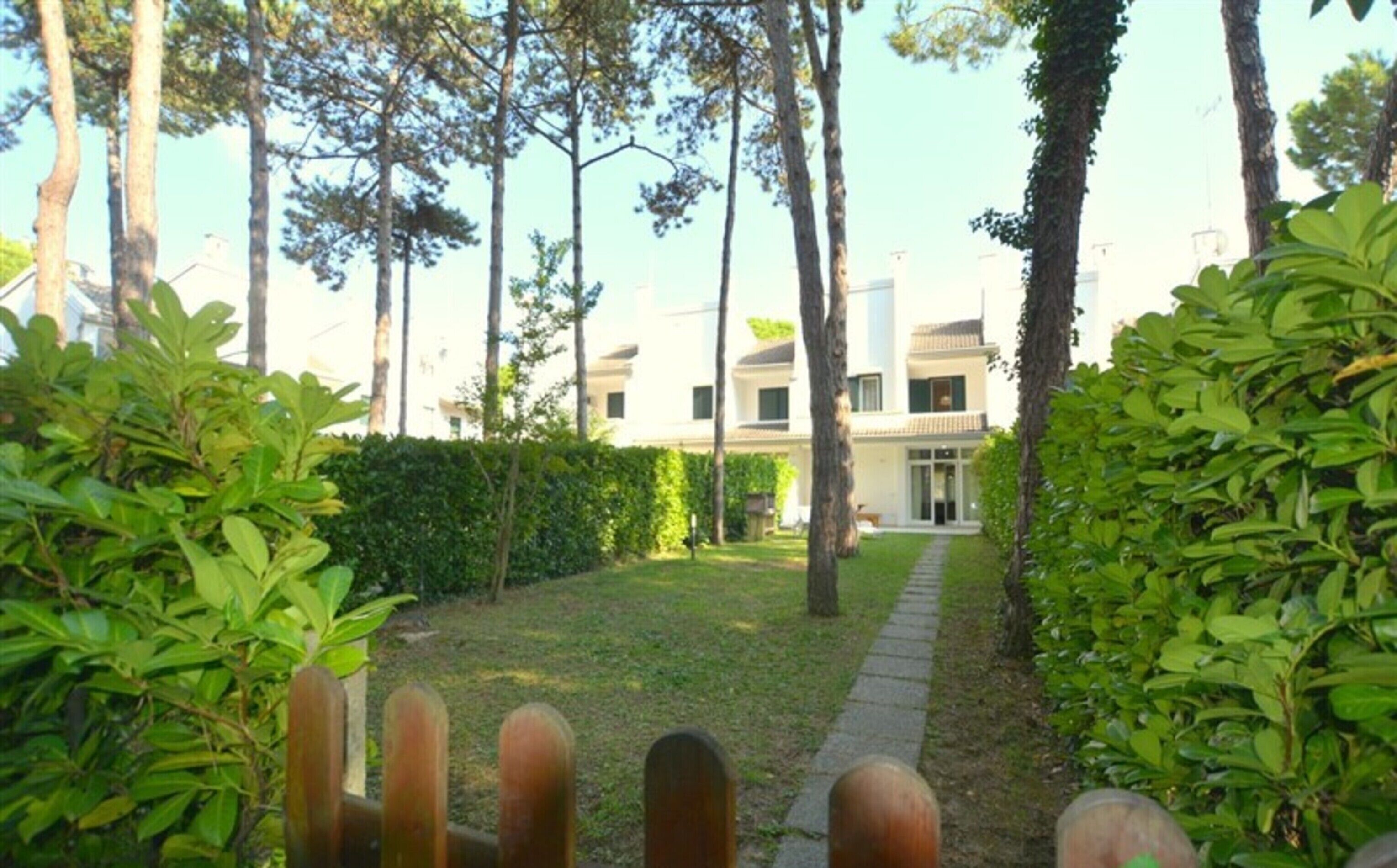 Een pad dat leidt naar een gebouw, omgeven door groen en bomen.