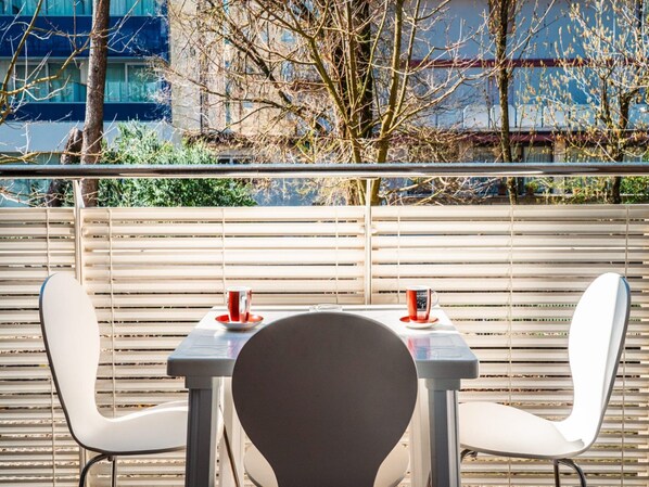 A table with two chairs and two red cups, set against a backdrop of a wooden fence and a building.