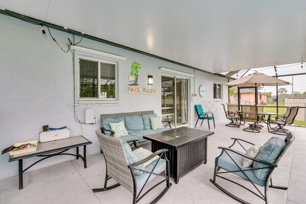 A covered patio area with outdoor furniture, including a sofa, chairs, and a table.