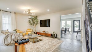 A modern living room with a sofa, coffee table, and decorative items. There is a staircase leading to another level. - Luxe & Cozy Gem: Walk to Beach & Boardwalk - Bikes (Atlantic City)