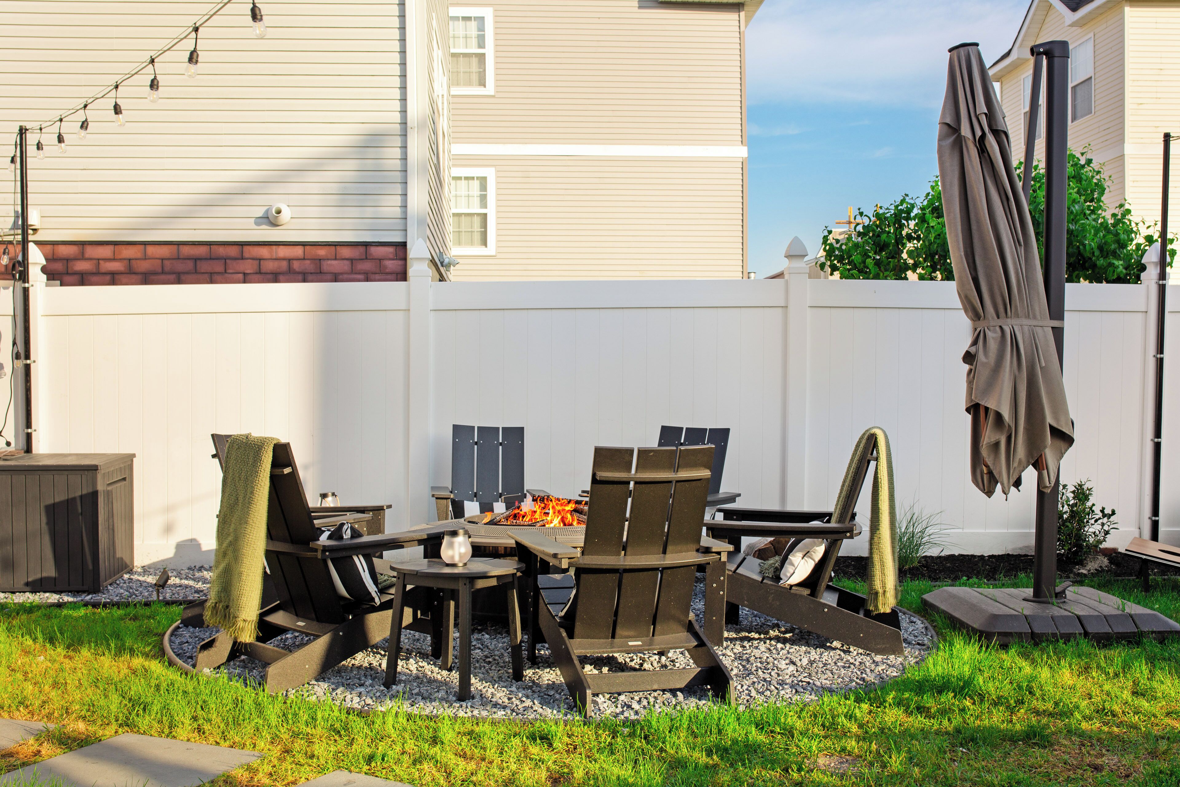 An outdoor patio with a fire pit, seating, and a pergola.