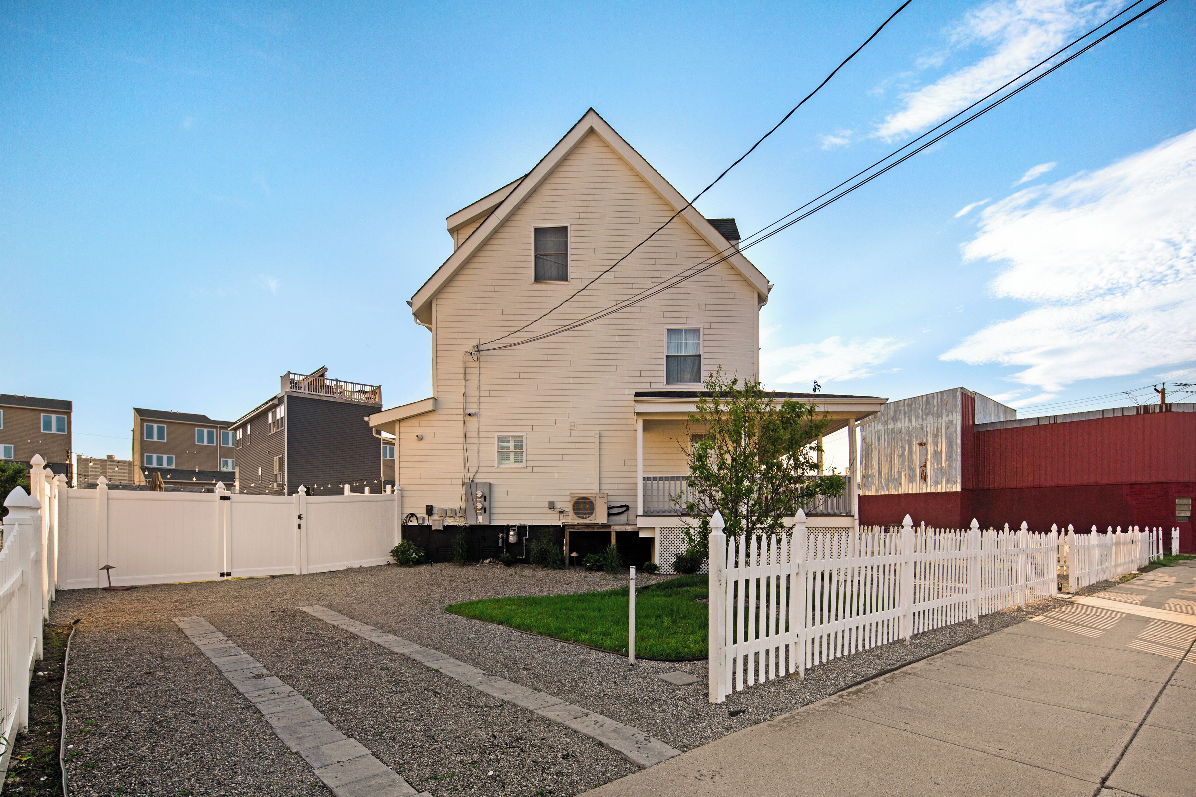 A two-story house with a front porch, a small front yard, and a white picket fence.