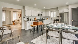 A modern kitchen with white cabinets, a central island, and a dining area with a glass table and chairs. - Luxe & Cozy Gem: Walk to Beach & Boardwalk - Bikes (Atlantic City)