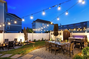 Um quintal com área de churrasqueira, área de estar externa e luzes pendentes.