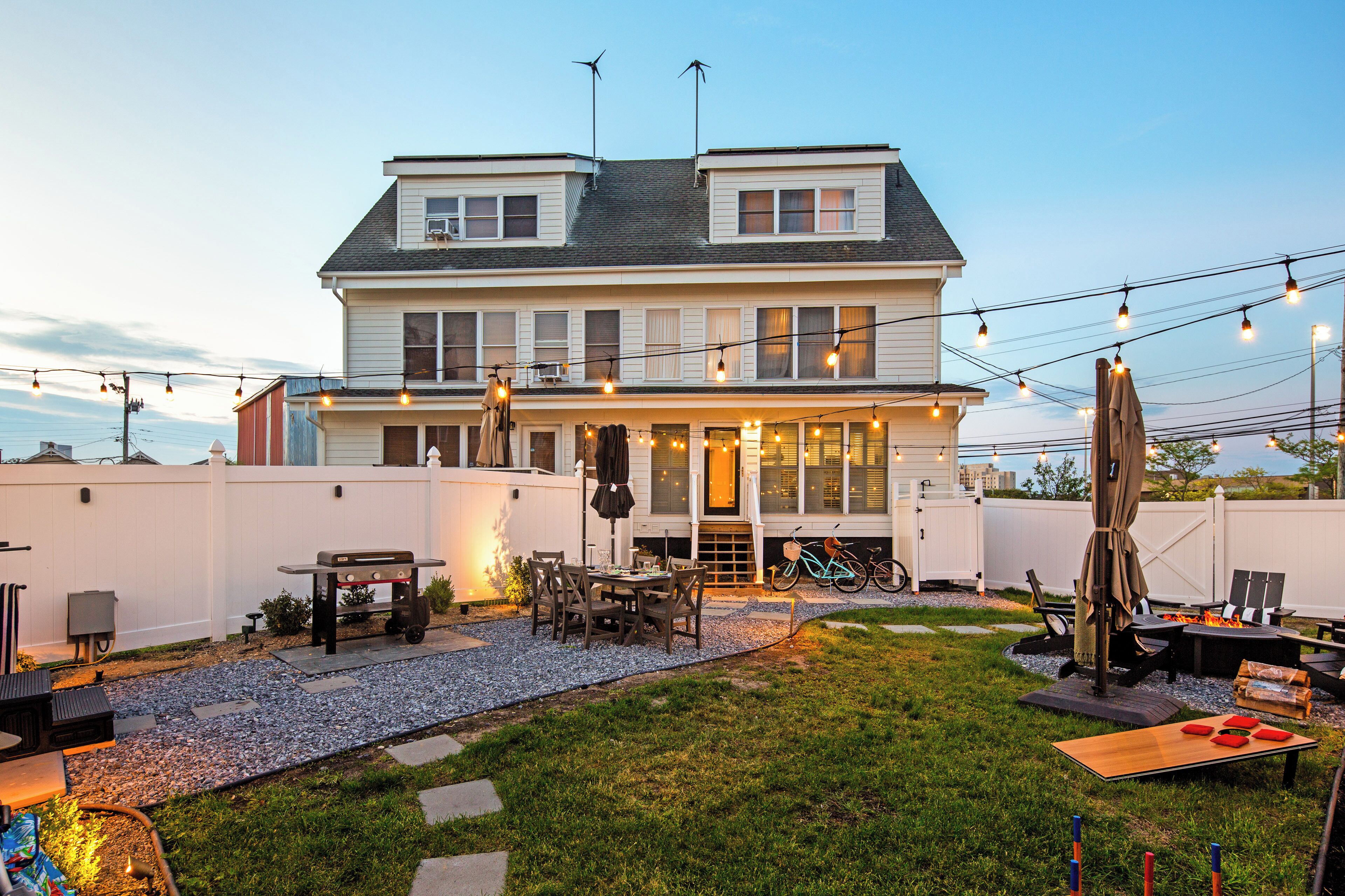 Une maison à deux étages dotée d’un patio, d’un espace salon extérieur et d’un barbecue.