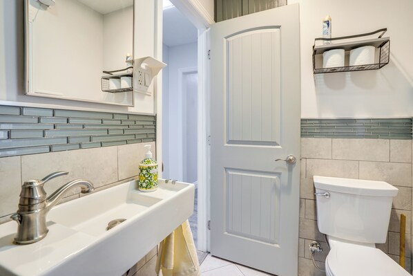Un baño con lavamanos blanco, inodoro y puerta.
