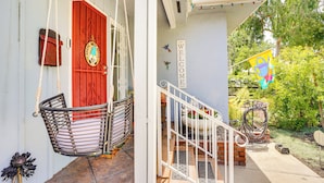 A porch with a red door, a hanging chair, and a welcome sign. - Guest Favorite Hot Tub Desks Quiet Oasis (Long Beach)