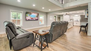 A spacious living area with a sectional sofa, a dining table, and a kitchen in the background.