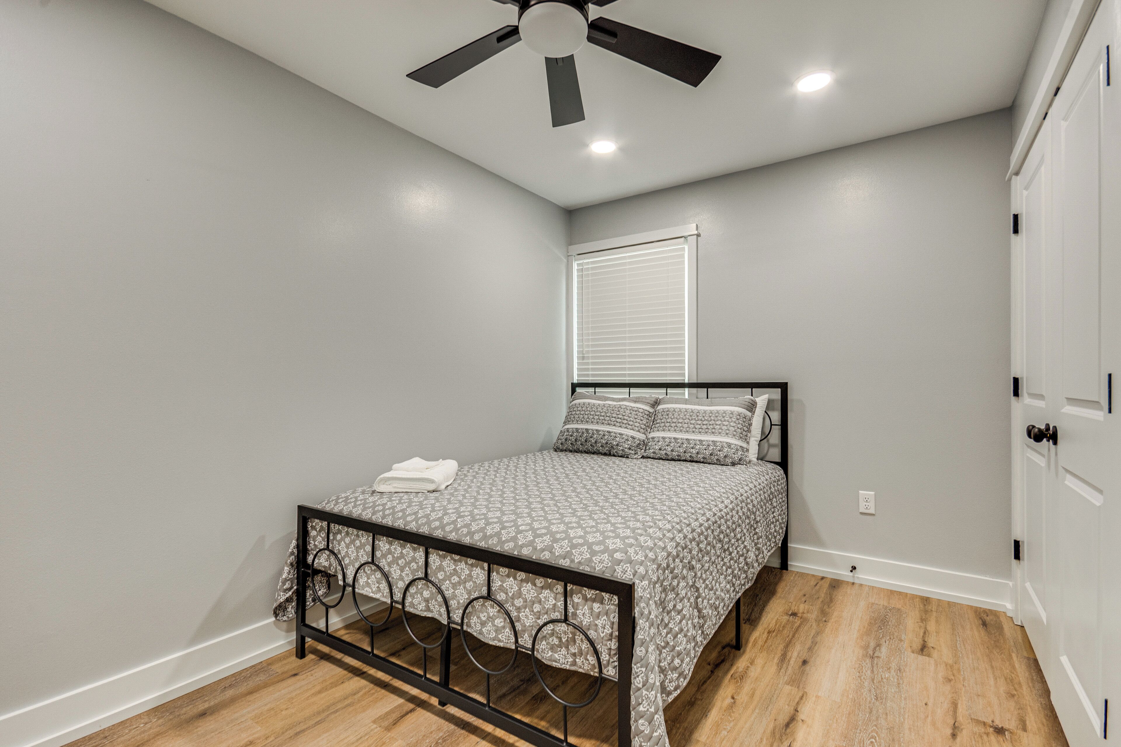 Une chambre à coucher avec un lit, un ventilateur de plafond et une fenêtre avec des stores.