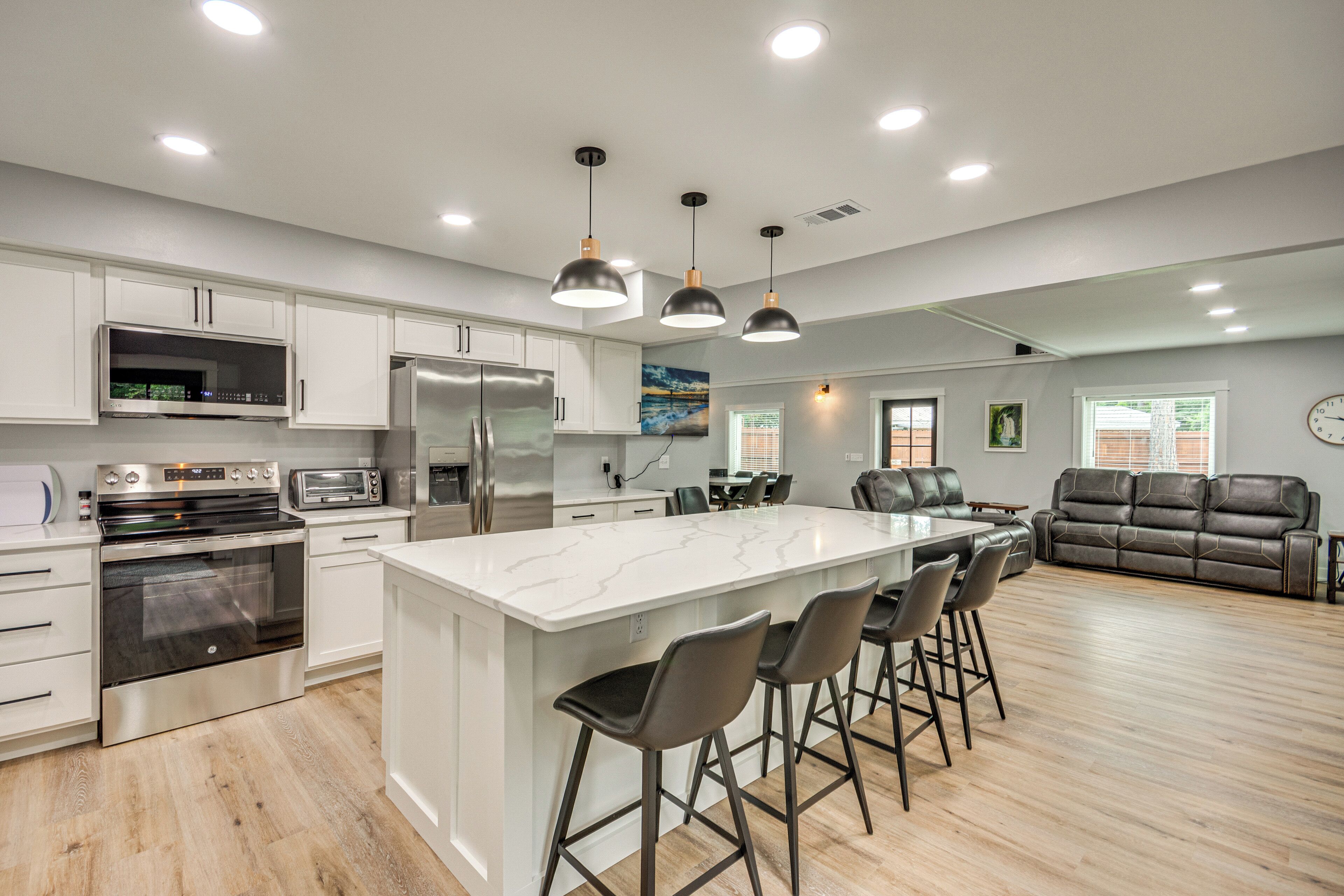A modern kitchen with white cabinets, stainless steel appliances, and a large island with bar stools.