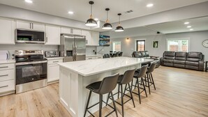 A modern kitchen with white cabinets, stainless steel appliances, and a large island with bar stools.