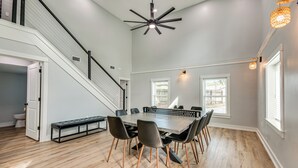 A spacious dining area with a large table and chairs, a staircase, and a ceiling fan.