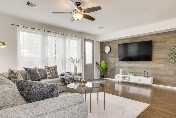 A modern living room with a sofa, coffee table, and a flat-screen TV mounted on a wooden wall.