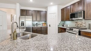A modern kitchen with granite countertops, stainless steel appliances, and dark wooden cabinets. - Golf, Bike, Fish & More: Family Getaway in Katy (Katy)