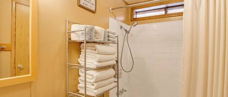 A bathroom with a shower, a towel rack, a toilet, and a sink.