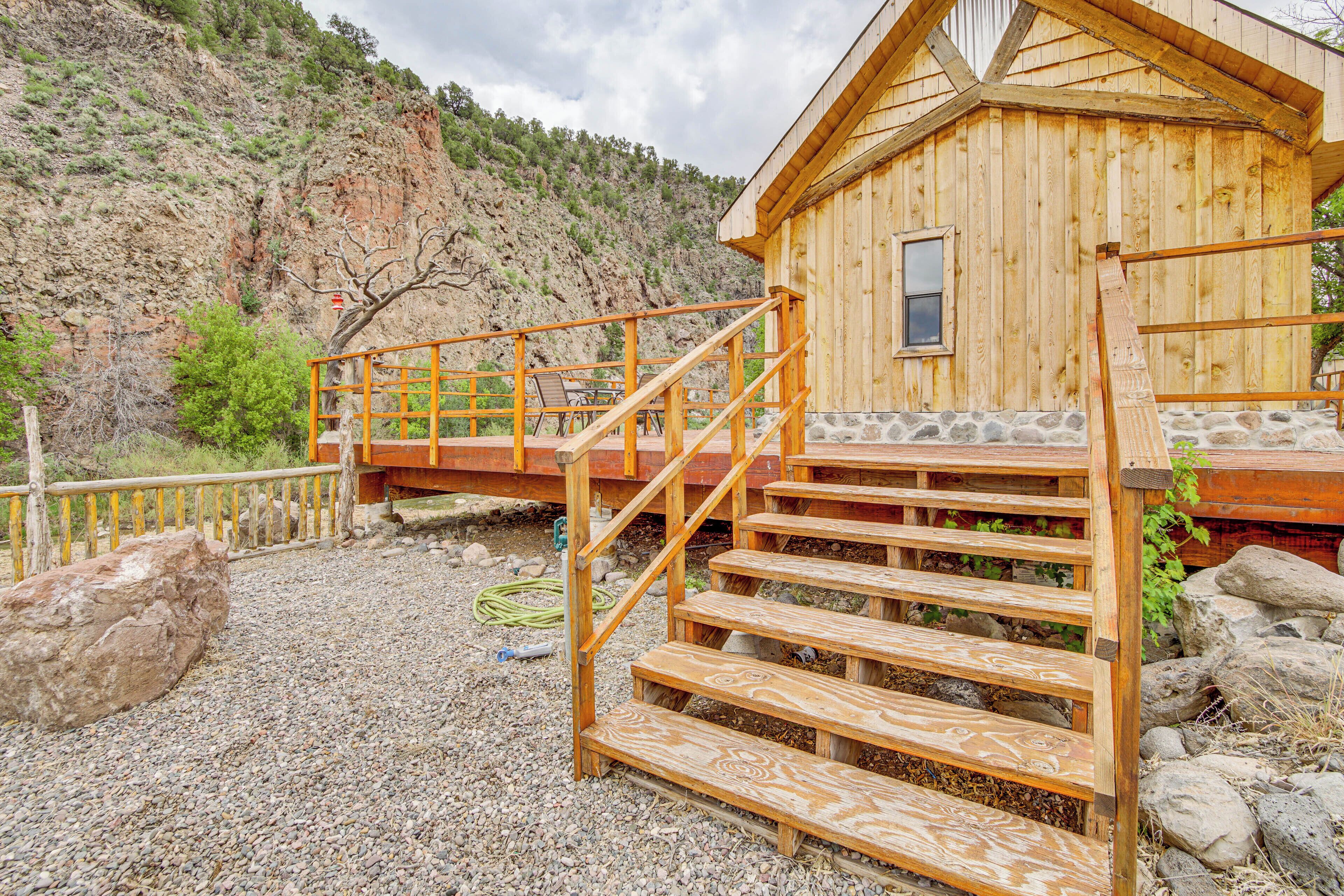 Une cabane en bois avec des fondations en pierre, un escalier en bois et une terrasse en bois.