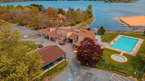 An aerial view of a lakeside property with a swimming pool, a covered parking area, and a building with a red roof. - Hot Tub & Community Beach: Albrightsville Home! (Albrightsville)