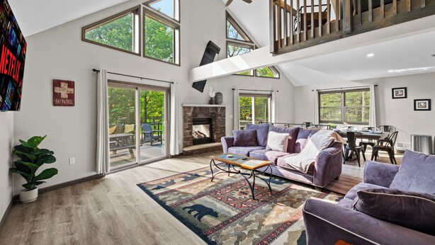 A spacious living area with a fireplace, large windows, and a high ceiling. - Hot Tub & Community Beach: Albrightsville Home! (Albrightsville)