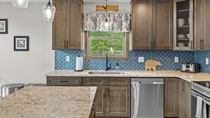 A kitchen with wooden cabinets, a granite countertop, a window with a view, and a sign above the window. - Hot Tub & Community Beach: Albrightsville Home! (Albrightsville)