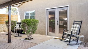 Un espace patio aménagé avec un fauteuil à bascule, un petit arbre et une porte-fenêtre coulissante.