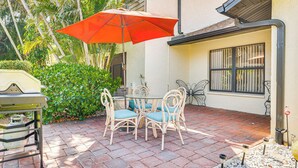 An outdoor patio with a table and chairs, a gas grill, and a red umbrella. - 5 Mi to Fort Myers Beach: Home w/ Large Yard! (Fort Myers)