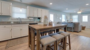 A spacious kitchen with white cabinets, a wooden island with bar stools, and a large window with blinds. - 1 Block to Gulf: Dauphin Island Retreat w/ Views (Dauphin Island)