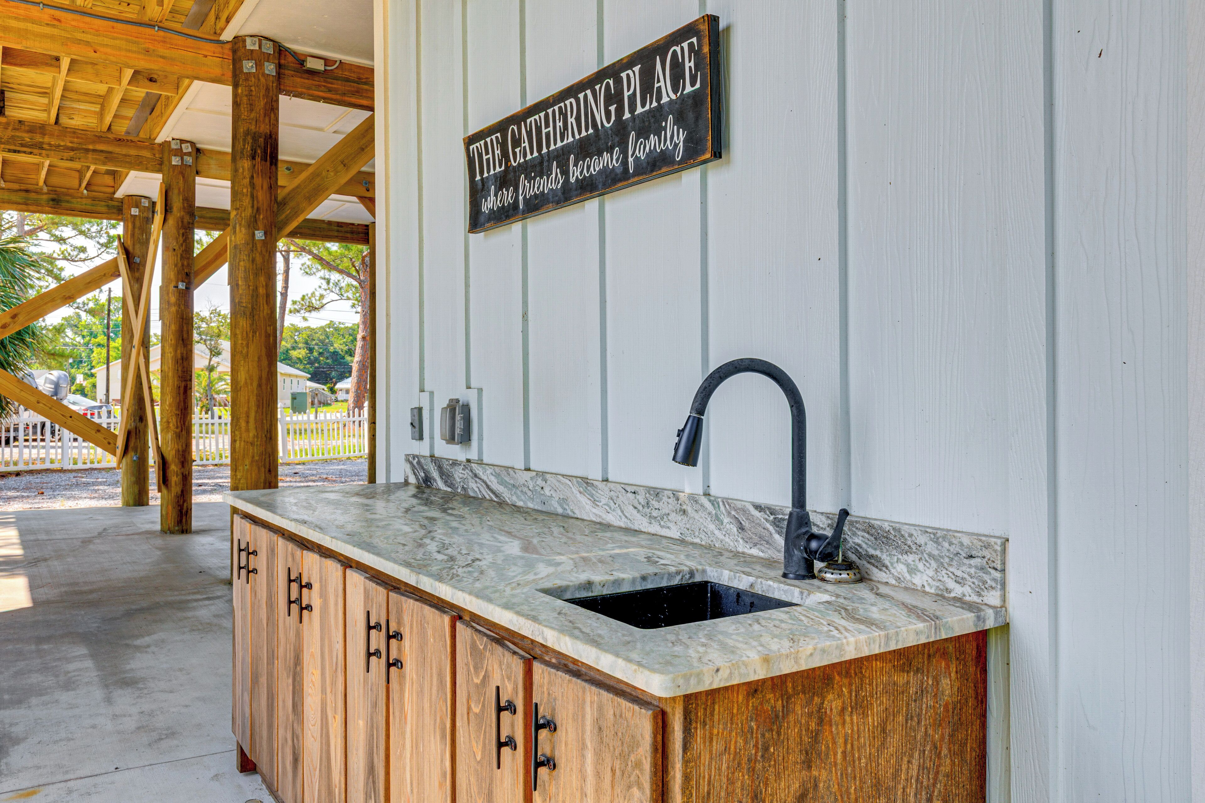 A kitchen with a marble countertop, wooden cabinets, and a black faucet.