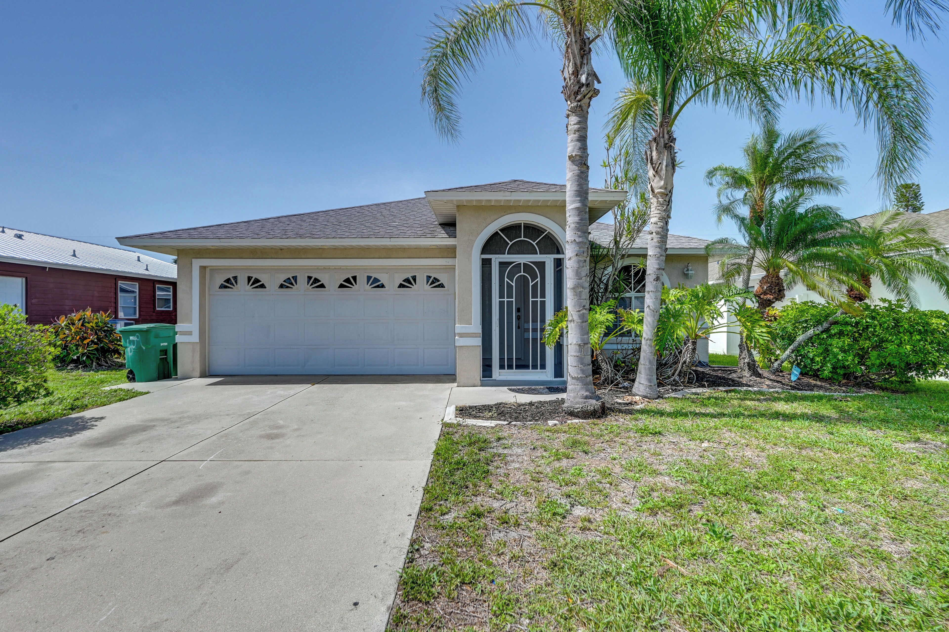 A single-story house with a garage, a palm tree, and a well-maintained lawn.