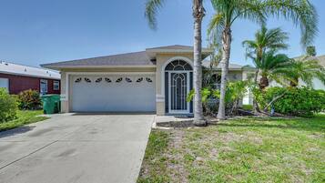 A single-story house with a garage, a palm tree, and a well-maintained lawn.