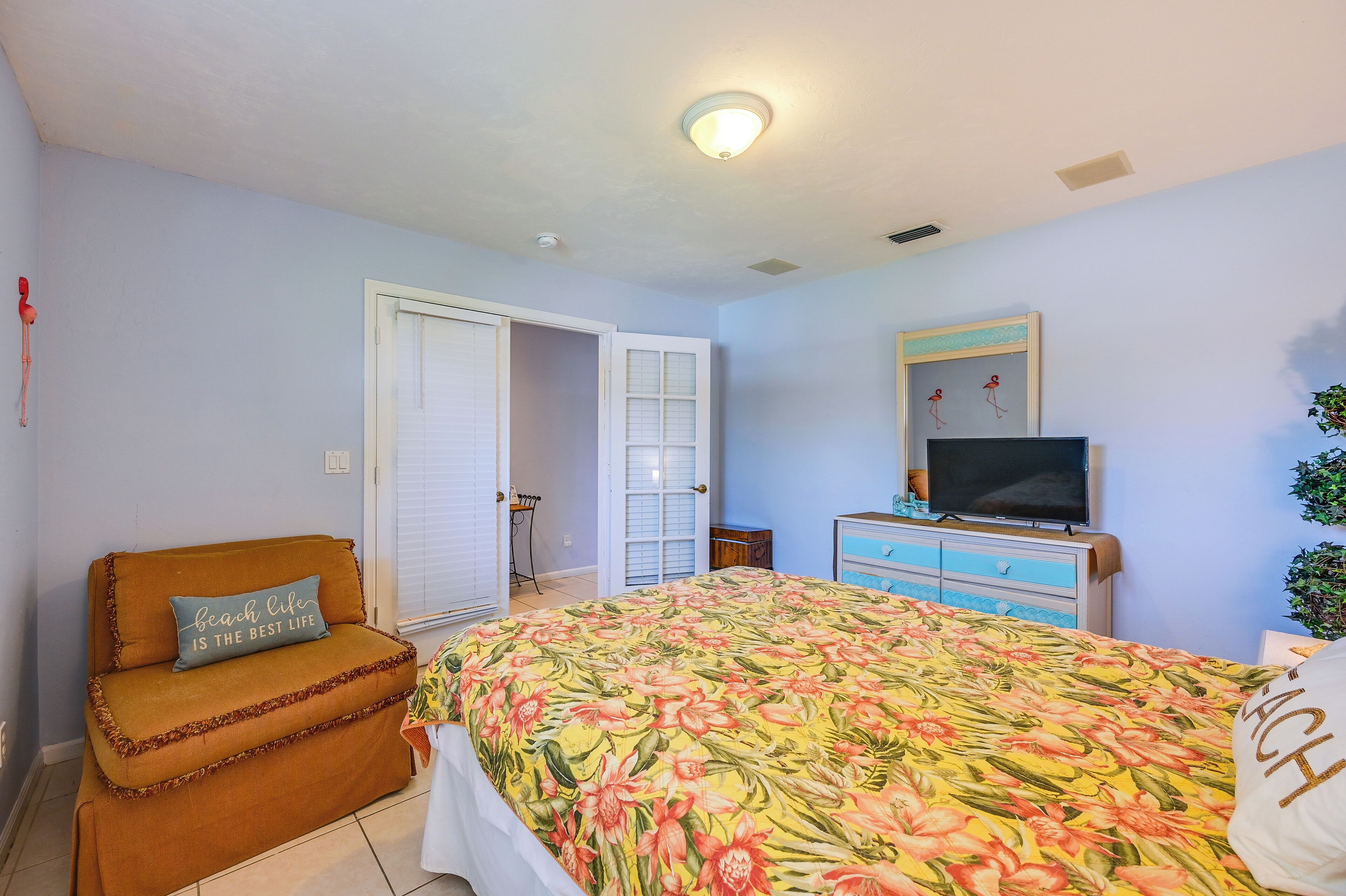 A bedroom with a bed, a sofa, a television, and a dresser.