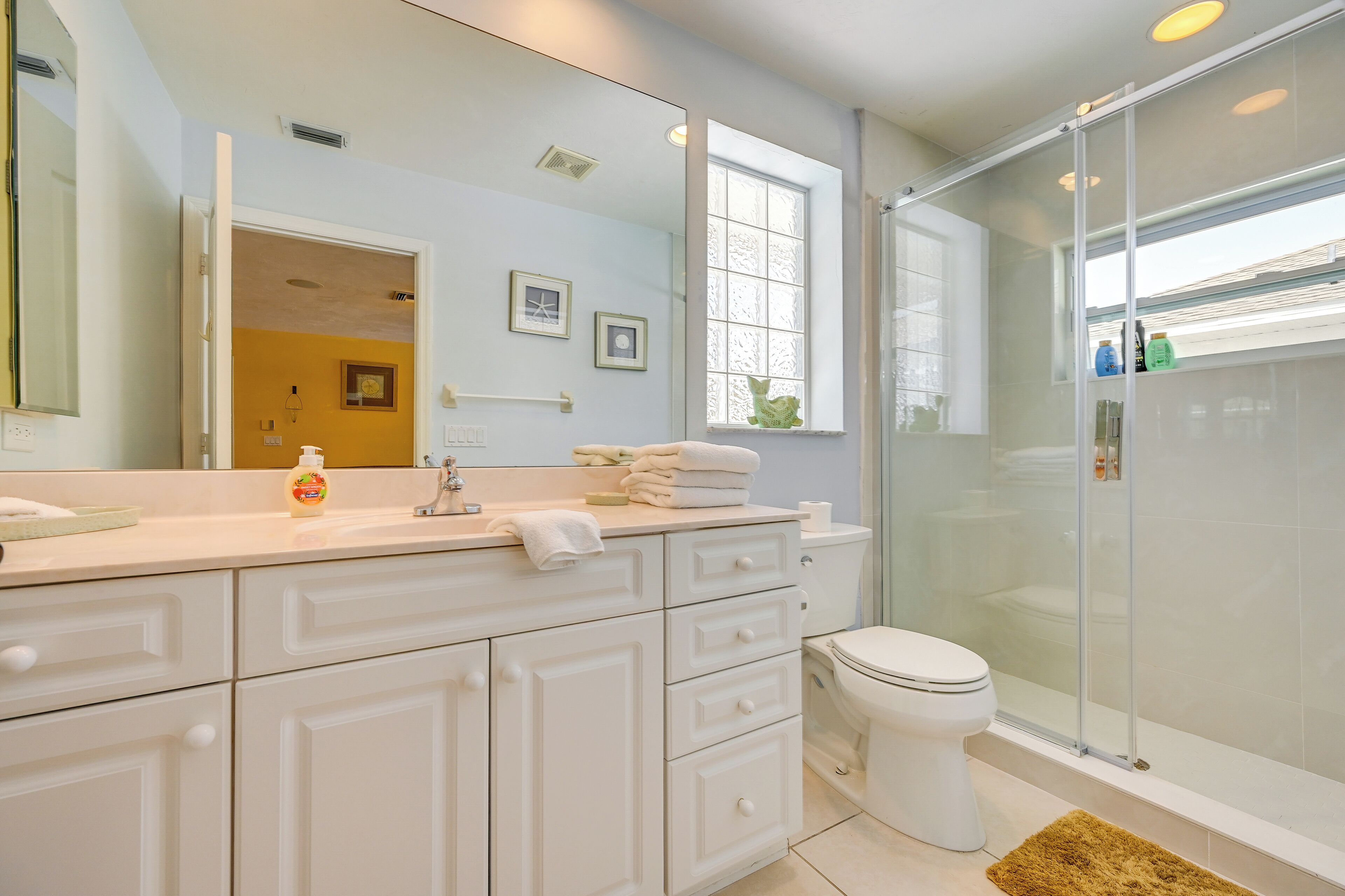 Une salle de bain moderne avec un meuble-lavabo blanc, une cabine de douche en verre et un grand miroir.