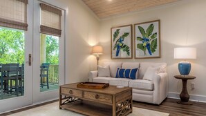 A living room with a white sofa, wooden coffee table, and two framed artworks on the wall. - Bayfront Gem Near Fishing in Dauphin Island (Dauphin Island)