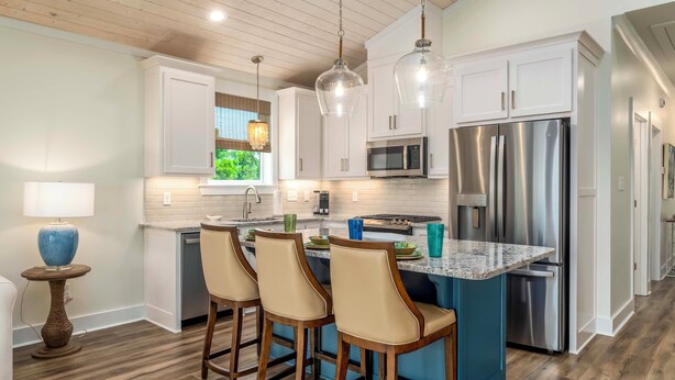 A modern kitchen with white cabinets, stainless steel appliances, and a central island with bar stools. - Bayfront Gem Near Fishing in Dauphin Island (Dauphin Island)