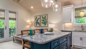A kitchen with a marble island, blue cabinets, and pendant lighting. - Bayfront Gem Near Fishing in Dauphin Island (Dauphin Island)