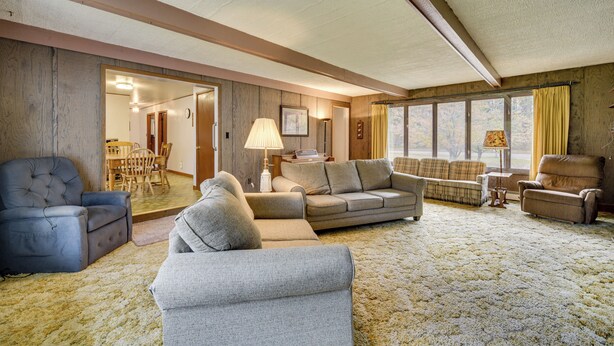 A spacious living room with a large sofa, a smaller armchair, and a blue armchair. There is a dining area visible through an open doorway. - Fisher's Retreat: Hayward Home, Near ATV Trails! (Hayward)