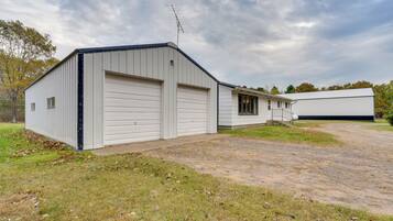 A single-story industrial building with two large garage doors, a small attached office, and a gravel driveway.