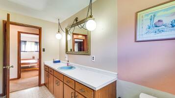 A bathroom with a wooden vanity, a blue sink, and a large mirror with a decorative frame.