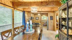 A wooden interior with a dining table, chairs, a chandelier, and a cabinet with decorative items. - Canal Across Street: Family Cabin in Breezy Point! (Pequot Lakes)