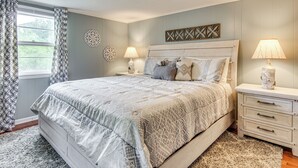 Une chambre à coucher avec un grand lit, deux tables de chevet avec des lampes, un élément décoratif mural et une fenêtre avec des rideaux.