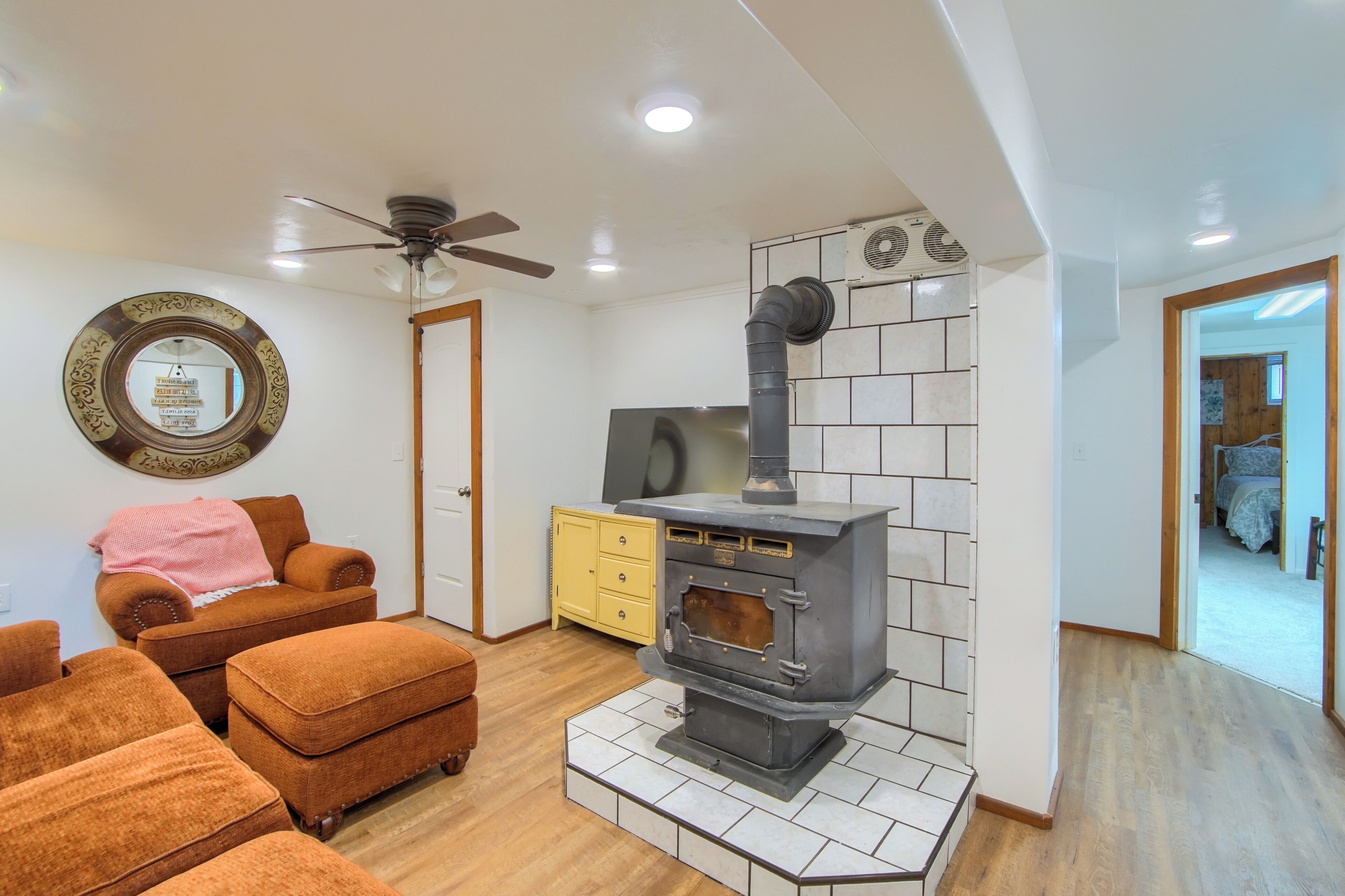 Una sala de estar con chimenea de leña, ventilador de techo y un mueble amarillo.