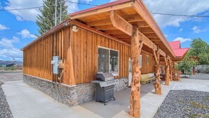 Eine Holzhütte mit Steinunterbau, einem Grill und einem überdachten Außenbereich.