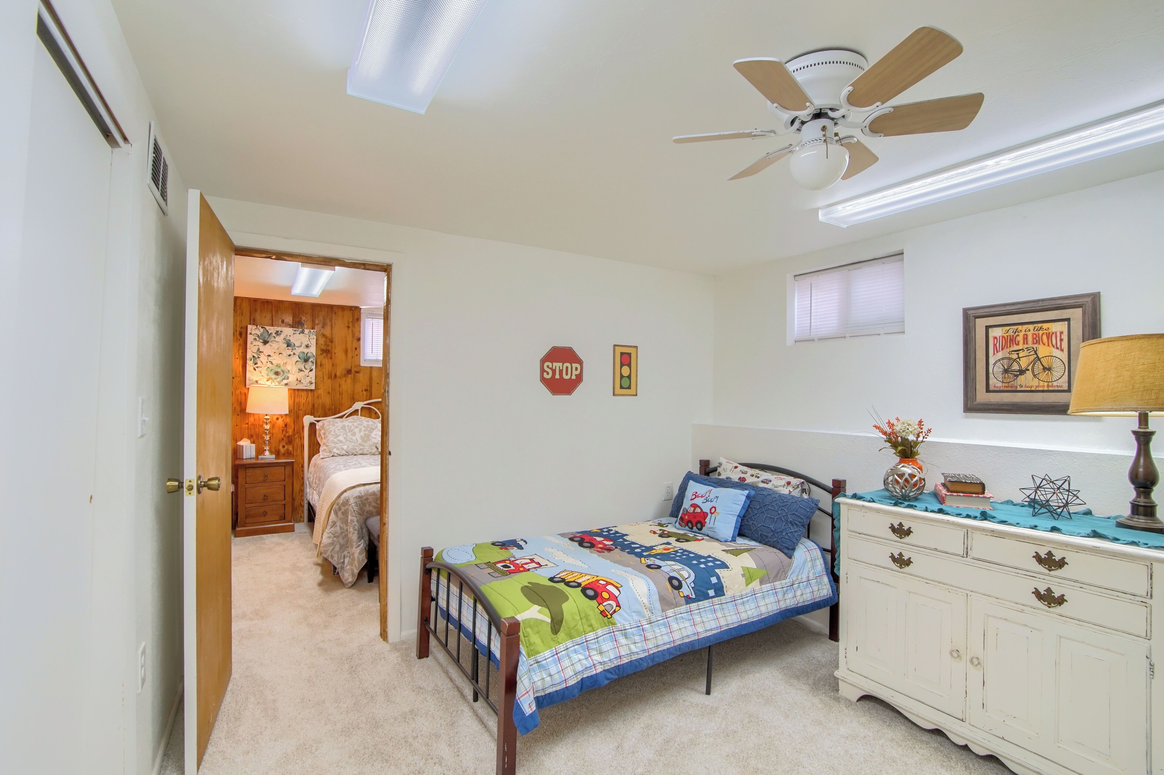 A bedroom with a bed, bedside table, dresser, and a ceiling fan.