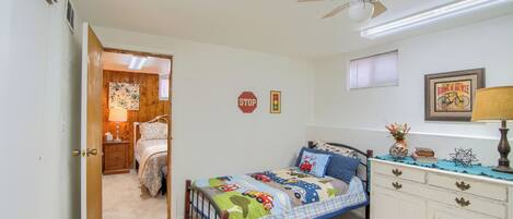A bedroom with a bed, bedside table, dresser, and a ceiling fan.