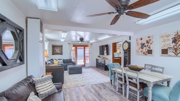 A spacious living area with a ceiling fan, a dining table with chairs, a sofa, and a large window with curtains. - Group Getaway w/ Mtn Views: Home in Circleville! (Circleville)