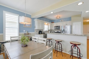 A modern kitchen with white cabinets, a wooden dining table, and bar stools. - Boater's Paradise! Galveston Bay Retreat w/ Slip (Galveston)